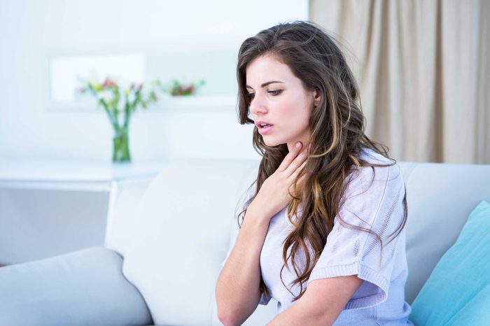 Sick woman on the couch with a sore throat.