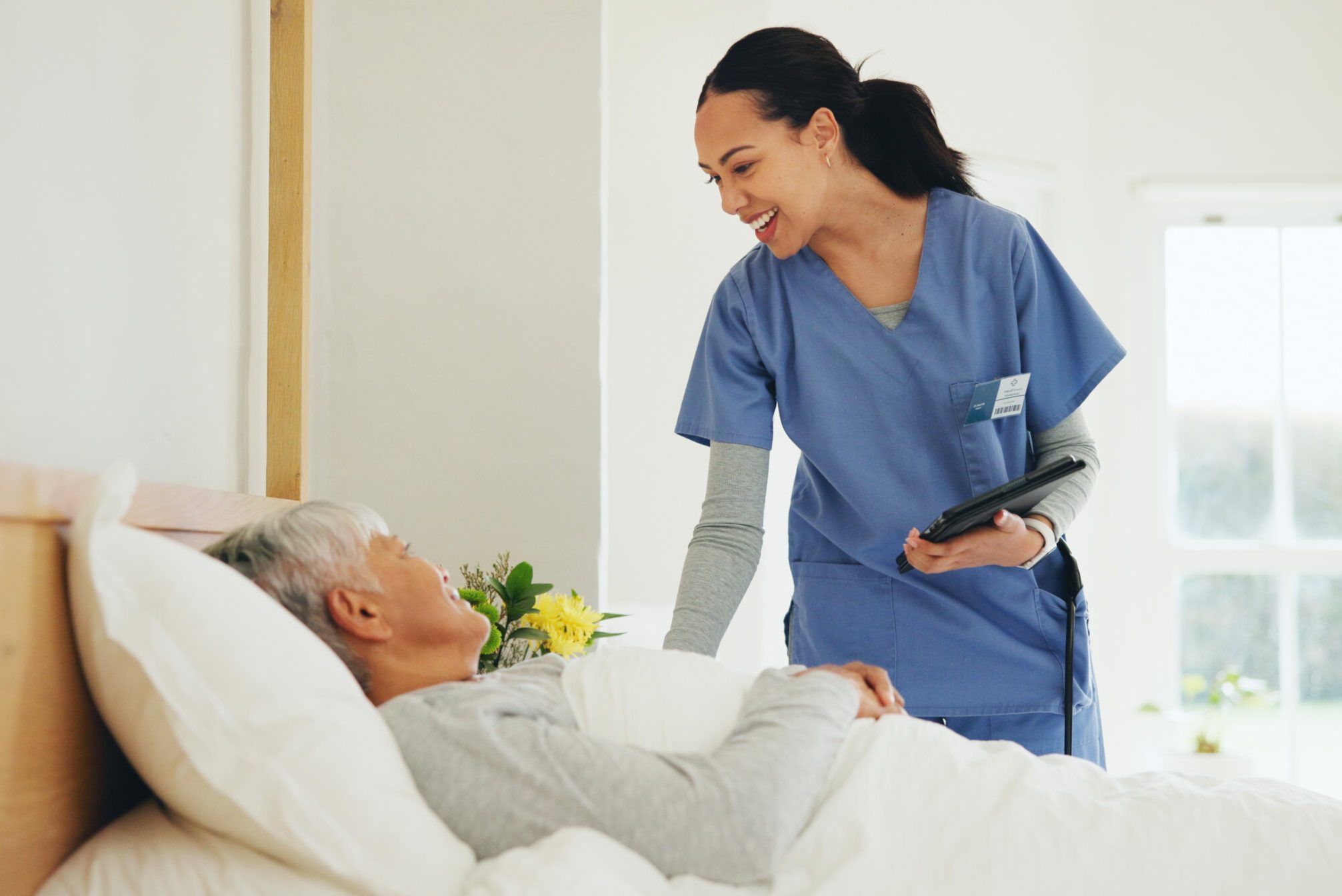 Happy woman, nurse and tablet with patient in bed, elderly care or checkup at old age home. Female person, doctor or medical caregiver smile with technology and client lying in bedroom for healthcare